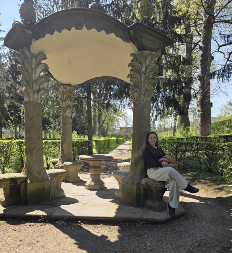 Person sitting under a stone gazebo in a park